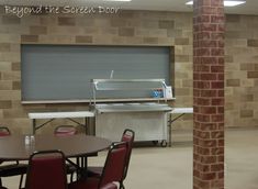 an empty room with tables and chairs in front of a screen door that says beyond the screen door