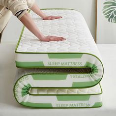 a person reaching for the mattress on top of two other mattresses in a room