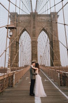 a bride and groom kissing on the brooklyn bridge