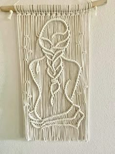 a white wall hanging on the side of a wall with ropes and knots attached to it