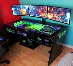 two computer monitors sitting next to each other on top of a wooden floor in front of a blue wall