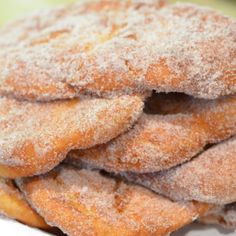 a pile of sugar covered donuts sitting on top of a white plate