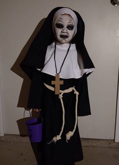 a person in a nun costume holding a bucket and wearing a cross on it's chest