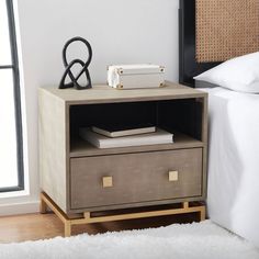 a nightstand with some books on it next to a bed