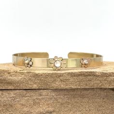 This is the ultimate in sweetness and luxury! At the center of this 14K solid yellow gold cuff bracelet is a diamond flower and at the flowers center is a totally clean, ethically sourced round rose cut diamond weighing .215 carats! On each side of the center flower are two more solid gold flowers - one in white gold and one in rose gold! This is the flower in your garden that will NEVER wilt and will always be there to remind you of spring and summer. The width of the cuff is 1/4 inches. Inner Yellow Gold Cuff Bracelet, Flower Cuff Bracelet, Diamond Cuff Bracelet, Floral Bracelet, Handmade Fine Jewelry, Diamond Gift, Gold Bracelet Cuff, Gold Cuffs, Diamond Flower