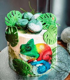 a colorful cake decorated with green leaves and an image of a chamelon