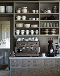 a coffee bar with lots of cups and saucers on the shelves above it,