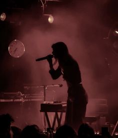 a woman standing on stage holding a microphone in front of an audience at a concert