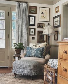 a living room filled with furniture and framed pictures on the wall above a chair next to a footstool