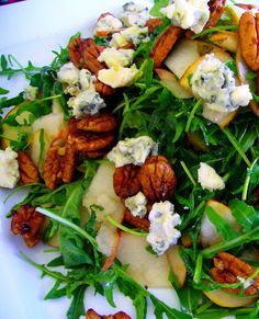 a white plate topped with green salad and pecans on top of it's leaves