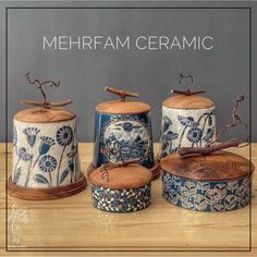 four ceramic canisters with lids and handles on a wooden table next to a sign that says mehrfam ceramics