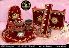 an assortment of red and gold items on a pink cloth with white flowers in the background