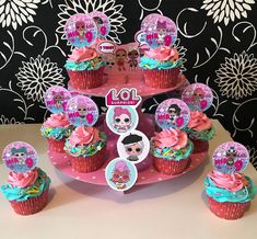 there are cupcakes with pink frosting and decorations on the cake stand in front of them