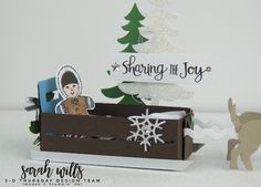 a christmas card in a box with an ornament next to it and a cutout of a person