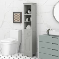 a white toilet sitting next to a gray cabinet in a bathroom with black and white floor tiles