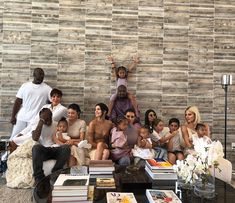 a group of people sitting around each other in front of a wall with books on it