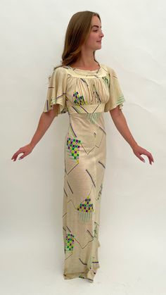 "This 1970s maxi dress is very much influenced by 1930s design and style with its repeating Art Deco geometric design and pretty, fluttery sleeves. The main colour is cream with the highlight colours in shades of green, lilac and purple. The fabric is acrylic which has a slight stretch. It is labelled inside 'Tina Warren Made in England'. There is a zip to the back and a hook and eye fastening.  The inside size label says '36' but this is an old size so please go by all the measurements here to see if it will fit you. When laid flat and fastened the measurements are: Length: 61\" inches Across the waist: 14\" inches Across the hips: 17\" inches From underarm to underarm across: 16\" inches Across the band under the bust: 13.5\" inches  It is in good overall condition with the following age Vintage Beige Short Sleeve Maxi Dress, Beige Short Sleeve Vintage Maxi Dress, Beige Vintage Short Sleeve Maxi Dress, Beige Vintage Maxi Dress With Short Sleeves, 1930s Design, White Cape, Lace Handkerchief, 1970s Dress, 1970s Style