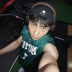 a young man with headphones on taking a selfie in front of some exercise equipment