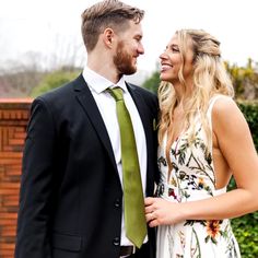 a man in a suit and tie standing next to a woman wearing a floral dress