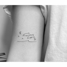 a small dolphin tattoo on the left inner arm, with stars and moon in the background