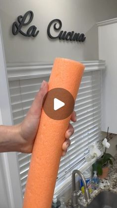 a person holding an orange roll of toilet paper in front of a kitchen sink with the word la cuota written on it