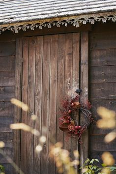 a wreath is hanging on the side of a wooden building with an old fashioned door