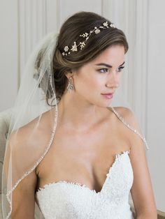 a woman in a wedding dress sitting on a chair wearing a veil and tiara