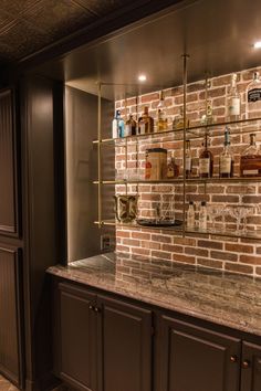 a brick wall with shelves and bottles on the top, along with marble counter tops