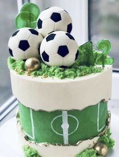 a cake decorated with soccer balls and grass