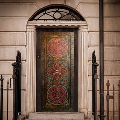 an ornate door on the side of a building with wrought iron fencing around it and a decorative glass panel