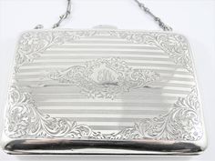 "This is a rectangular shaped lady's sterling silver  monogrammed purse. The purse has a beautiful flower and frond floral design etched on it with a  pin striped background pattern front and back. The middle section of the front of the purse is engraved with the initials \"EMM \" in an ornate script with a floral motif around it. The inside of the purse has a light brown leather lining divided into various sections. The purse has a 15 inch strap made up of oval and round shaped silver links. Th Silver Purse, Silver Monogram, A Beautiful Flower, Birmingham England, Light Brown Leather, Striped Background, Photo Locket, Purse Pouch, Beautiful Flower