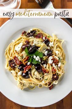 a white plate topped with pasta and olives