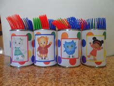 four children's toothbrushes in tins with pictures on them sitting on a counter