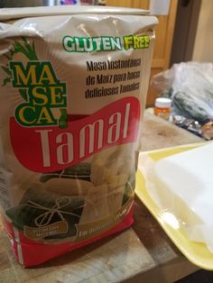 a bag of tamal sitting on top of a wooden table next to a cutting board