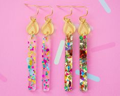 three pairs of earrings on a pink background with confetti sprinkles