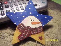 a wooden snowman star ornament sitting next to a remote control