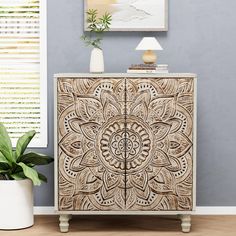 a white and brown cabinet sitting next to a potted plant