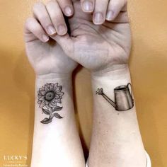 two people with matching tattoos on their wrists holding hands and one has a watering can