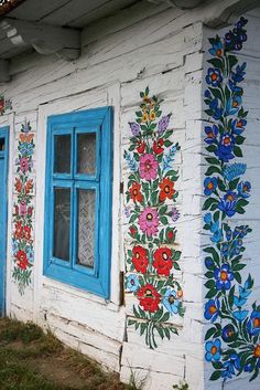 an old building with painted flowers on the side and blue window panes in front