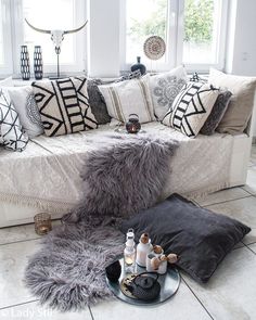 a living room filled with lots of pillows and blankets on top of a white couch