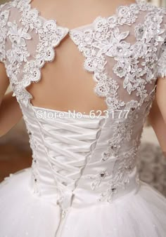 the back of a wedding dress with white flowers on it