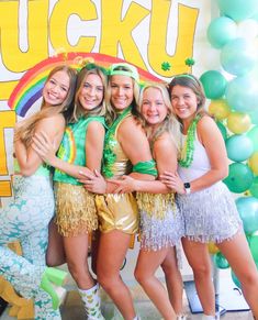 a group of young women standing next to each other in front of a wall with balloons