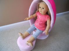 a doll is sitting in a pink chair