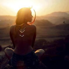 a woman sitting on top of a rock holding a yellow frisbee