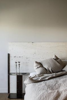 a bed with white sheets and pillows on top of it next to a night stand