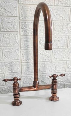 an old fashioned faucet is shown against a white brick wall and has two copper colored handles