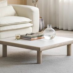 a living room with a couch, coffee table and books on the floor in front of it