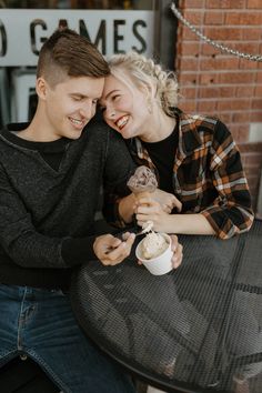 a man and woman sitting at a table eating ice cream