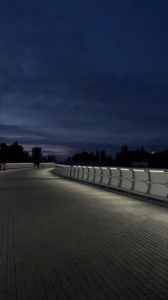 an empty walkway lit up at night with the lights on