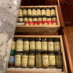 spices are stored in wooden boxes on the counter top next to an open spice rack